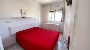 A bedroom with a bed, a dresser, a television, and a window with curtains. - 1 BR Sea View · Steps to Beach · Los Cristianos (Los Cristianos)