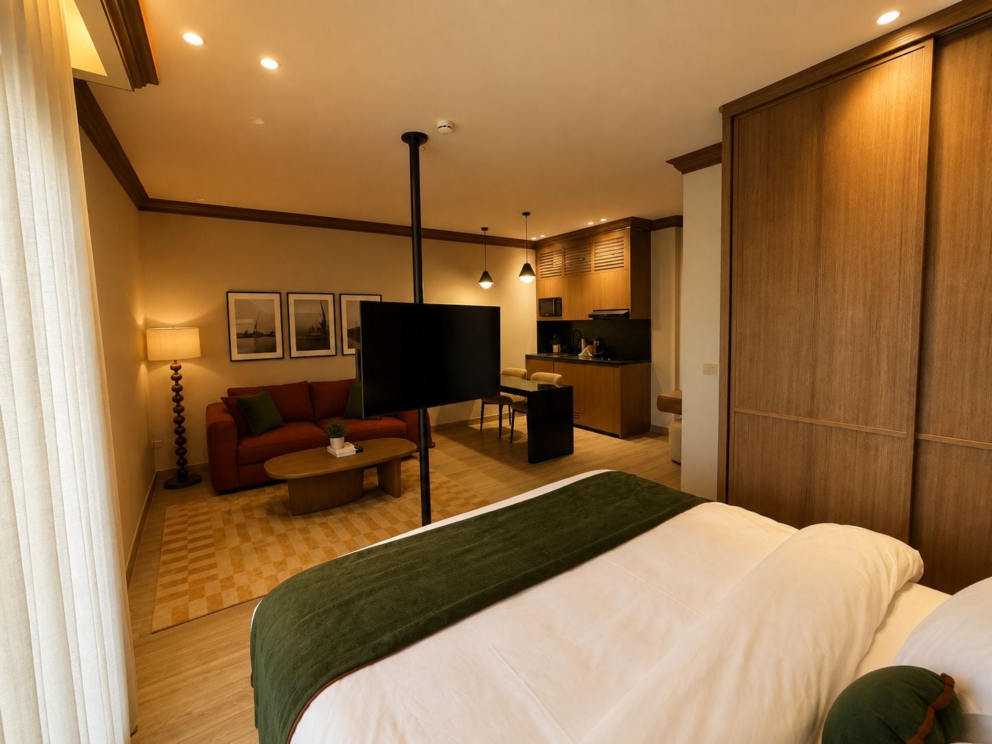 Een hotelkamer met een bed, een slaapbank, een salontafel, een televisie, een bureau en een kitchenette.