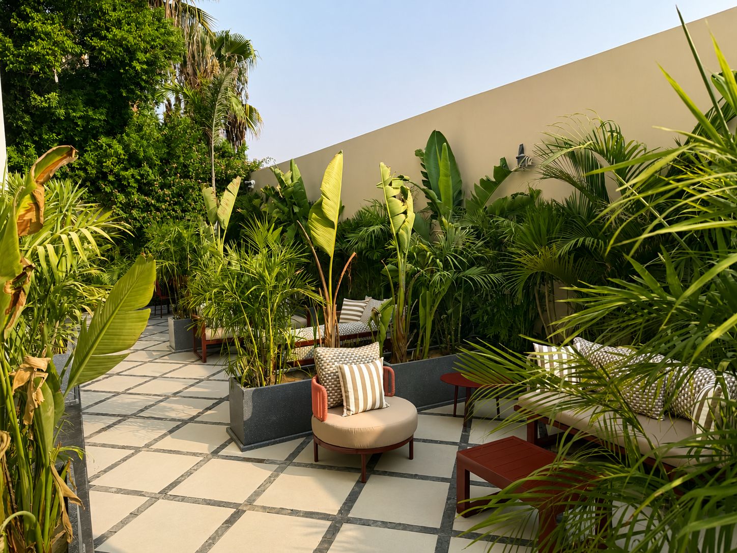 A rooftop garden with seating areas, potted plants, and a tiled floor.
