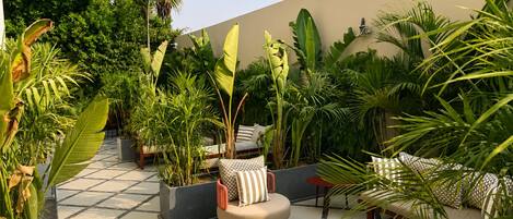 A rooftop garden with seating areas, potted plants, and a tiled floor.