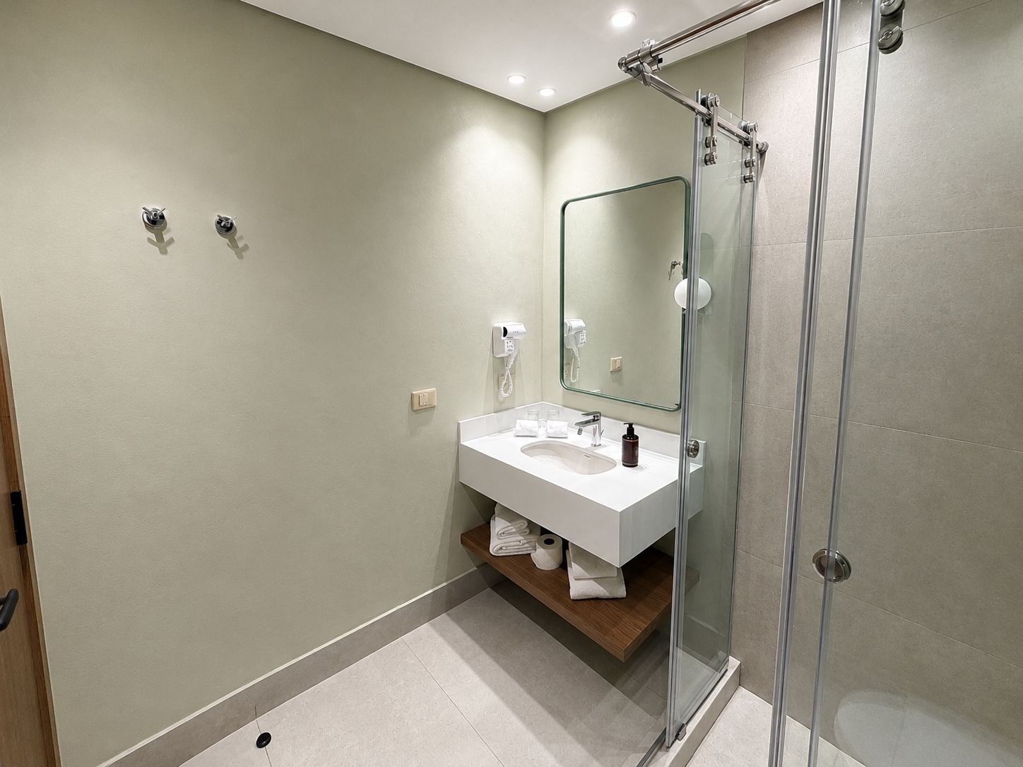 A modern bathroom with a glass shower enclosure, a white sink, and a mirror.