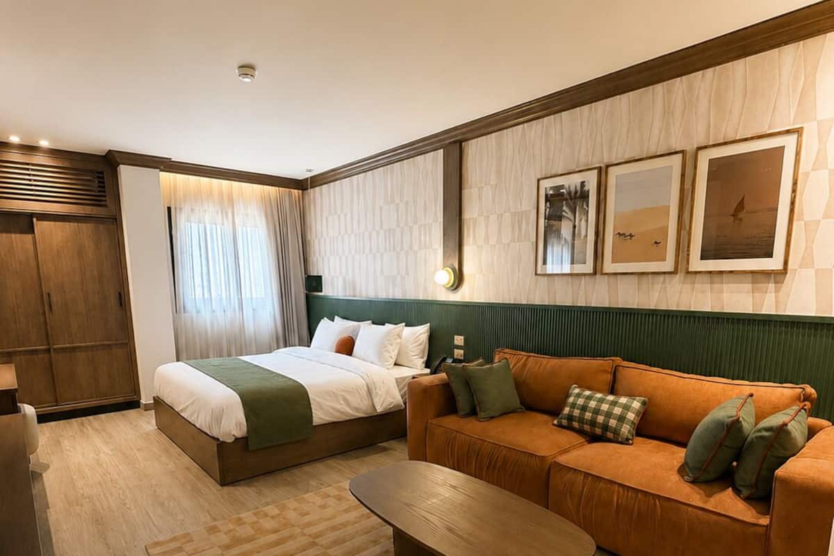 Una habitación de hotel con cama, sofá, mesa de centro y armario.