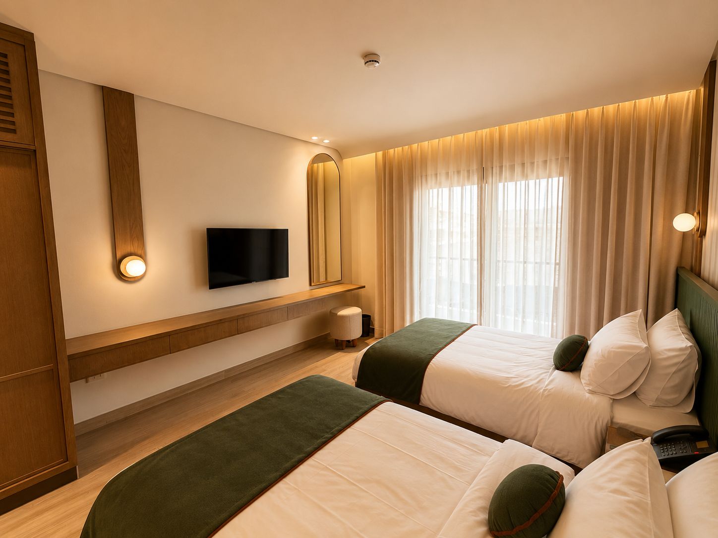 Ein Hotelzimmer mit zwei Betten, einem Fernseher, einem Nachttisch und einem Fenster mit Vorhängen.