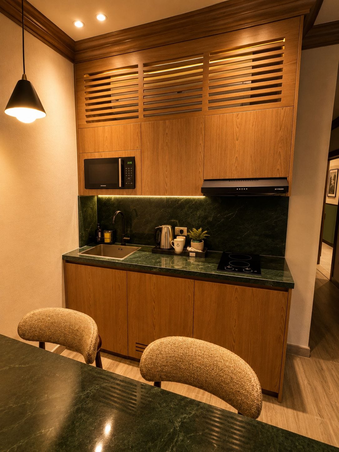 A compact kitchen with wooden cabinets, a built-in microwave, a stove, and a sink. There are two chairs and a table in the dining area.