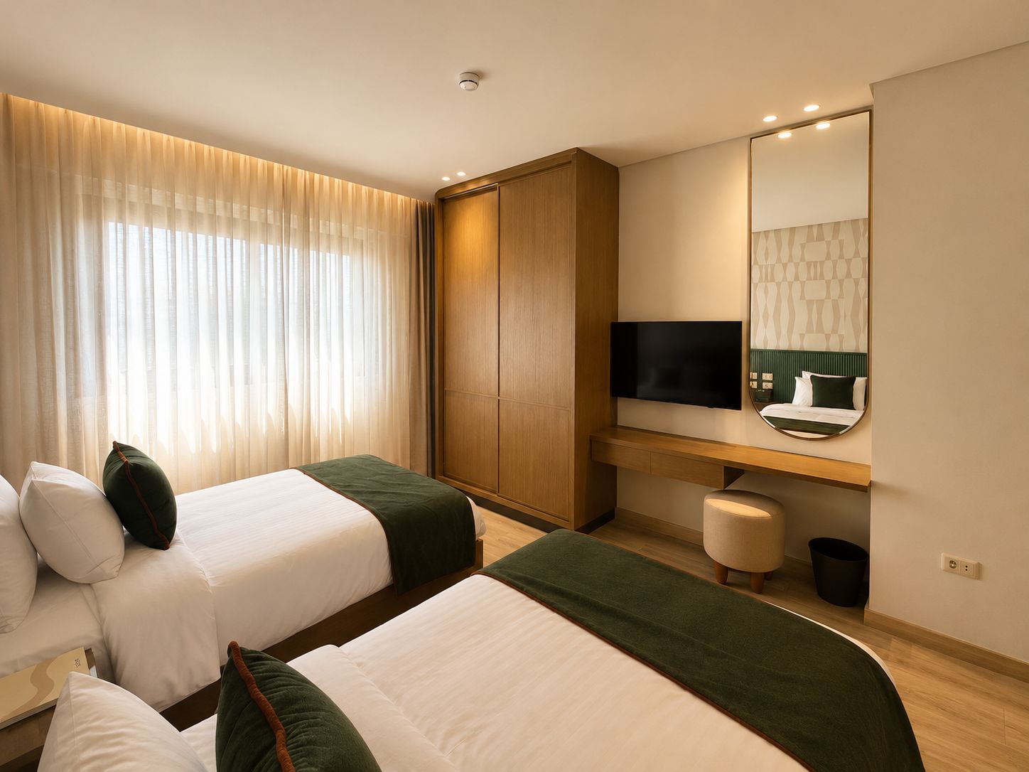 Ein Hotelzimmer mit zwei Betten, einem Fernseher, einem Schreibtisch und einem Spiegel.