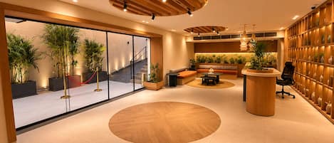 A modern interior with a reception desk, seating area, and a staircase leading to an upper level.