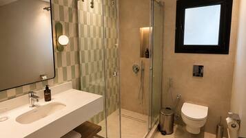 A modern bathroom with a glass-enclosed shower, a large mirror, and a white sink.