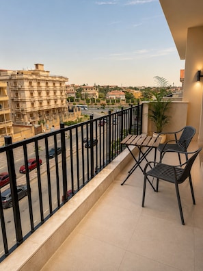 A balcony with a view of a residential area, a table with chairs, and a potted plant.