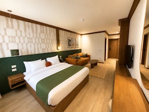 A hotel room with a large bed, a sofa, a TV, and a wooden floor. - NOMA New Cairo (New Cairo)