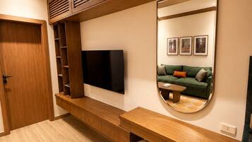 Uma sala de estar moderna com televisão de tela plana, prateleiras de madeira, um sofá e um espelho.