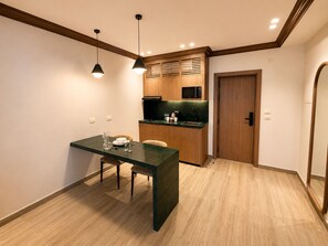 A compact kitchen with a dining area, wooden cabinetry, a microwave, and a door. - NOMA New Cairo (New Cairo)