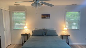 A bedroom with a bed, two bedside lamps, a ceiling fan, and two windows with blinds. - Spacious and marvelous studio with AC in quiet urban setting (Raleigh)