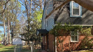 A pathway leading to a house with a brick exterior and a covered porch. - Spacious and marvelous studio with AC in quiet urban setting (Raleigh)