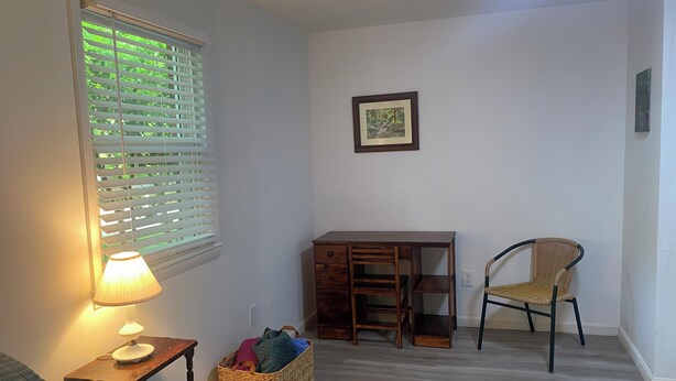 A room with a desk, a chair, a lamp, a basket, and a framed picture on the wall. - Spacious and marvelous studio with AC in quiet urban setting (Raleigh)