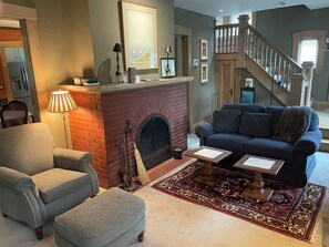 A living room with a fireplace, a sofa, an ottoman, and a coffee table.