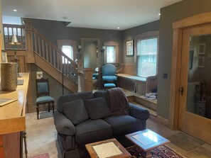 A living room with a sofa, coffee table, and a staircase leading to a loft.