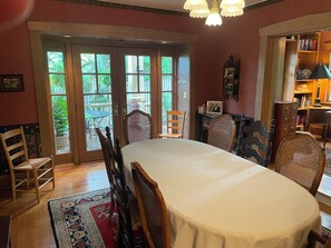 A dining area with a large table, chairs, and a view through French doors to a patio.