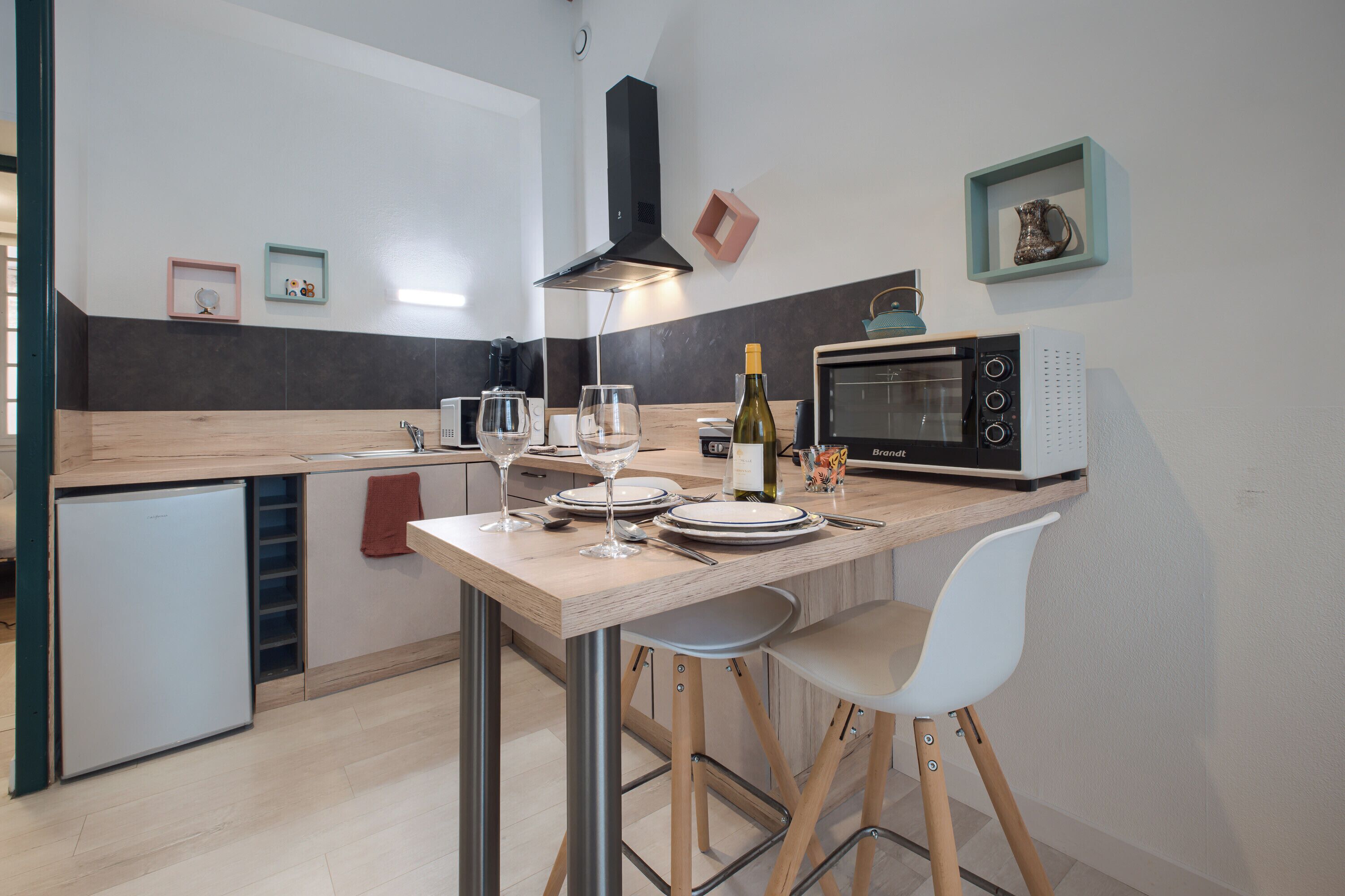 A modern kitchen with a built-in microwave, a wine bottle, and two bar stools.