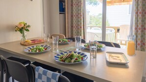 A dining table with plates of food, glasses, and a juice pitcher. - Oléon - Confort 2 TV – 5p  (2) (Saint-Georges-d'Oléron)