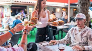 Een groep mensen dineert buiten, terwijl een bediende eten serveert.