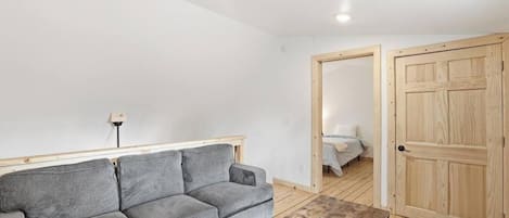 A room with a grey sofa, a wooden coffee table, and a wooden door.
