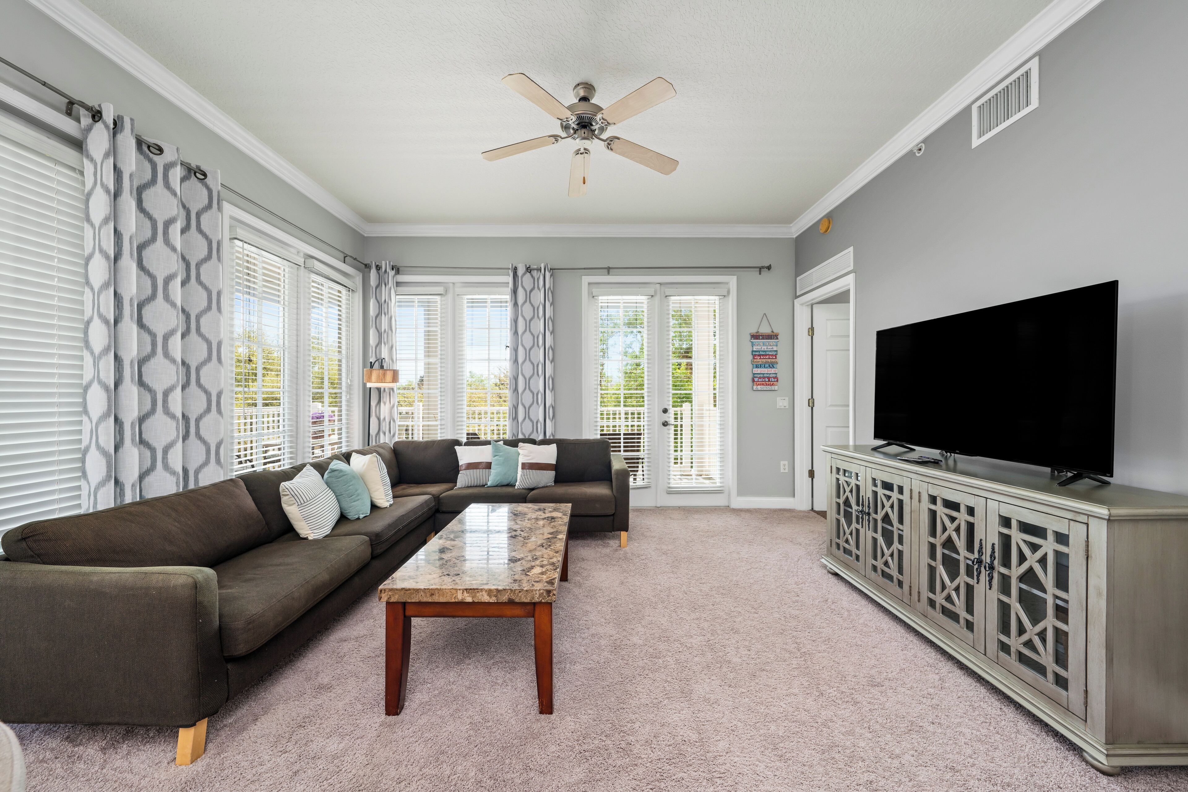 A living room with a sofa, coffee table, TV, and a ceiling fan.