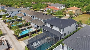 A residential area with modern houses, a swimming pool, and a large glass-enclosed deck. - Theater | Themed Kids Bedrooms | Games Room | Private Pool (Kissimmee)