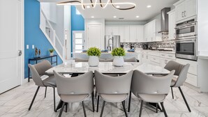 A modern kitchen with white cabinets, stainless steel appliances, and a marble countertop. - Theater | Themed Kids Bedrooms | Games Room | Private Pool (Kissimmee)