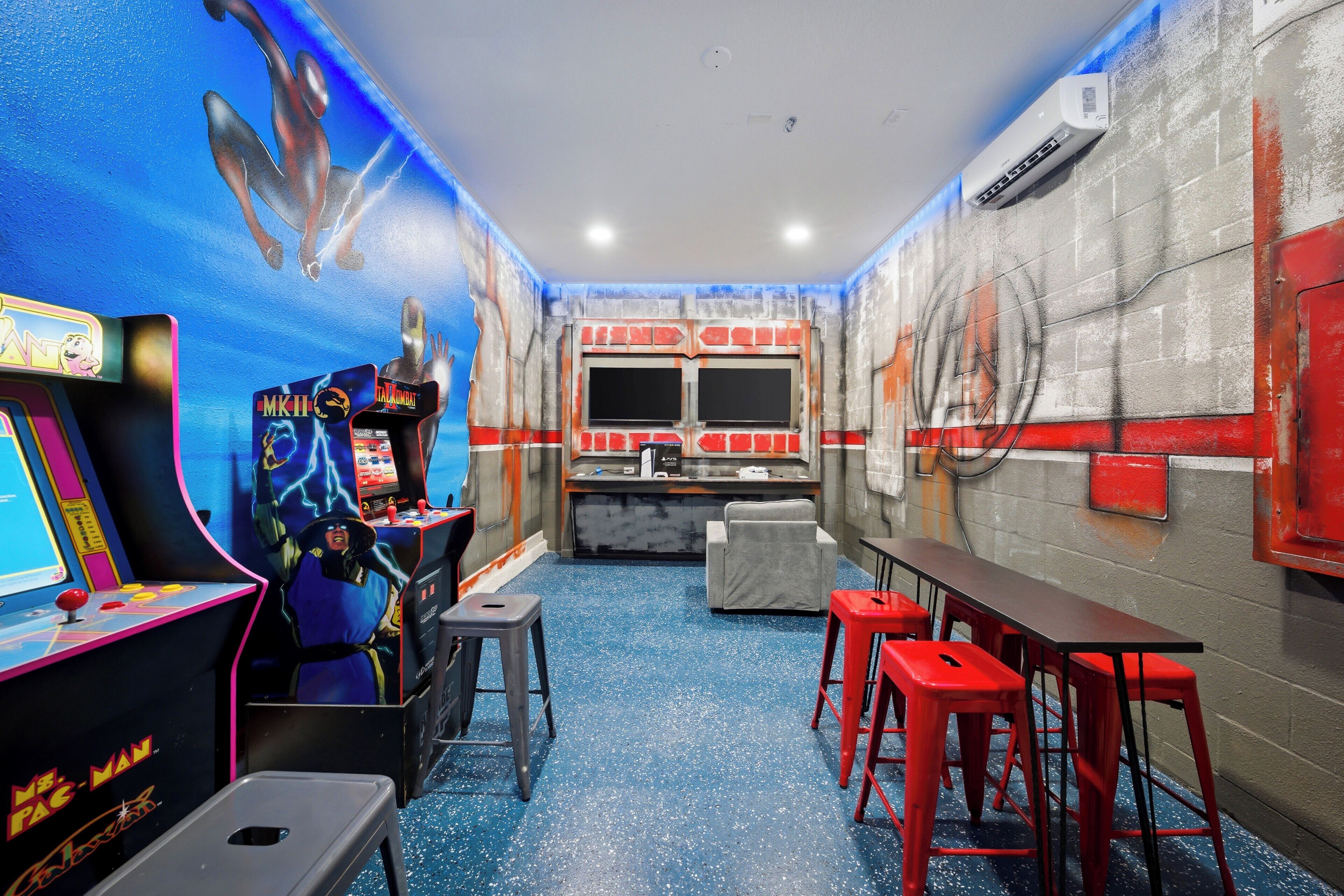 Um quarto com jogos de fliperama, um balcão e banquetas vermelhas.