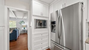 Une cuisine moderne avec des meubles blancs, un réfrigérateur en acier inoxydable et un four.