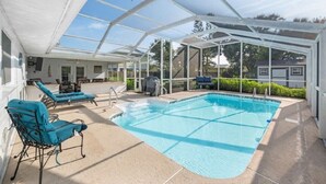 Une piscine extérieure couverte, dotée de chaises longues, d’un barbecue et d’un espace patio.