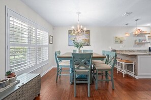 A dining area with a wooden table and chairs, a chandelier, and a view through large windows. - Island Retreat, Home with Pool & Beach Access (St. Augustine)