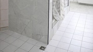 Un baño con separador de mármol, cortina de ducha y ventana con vistas.