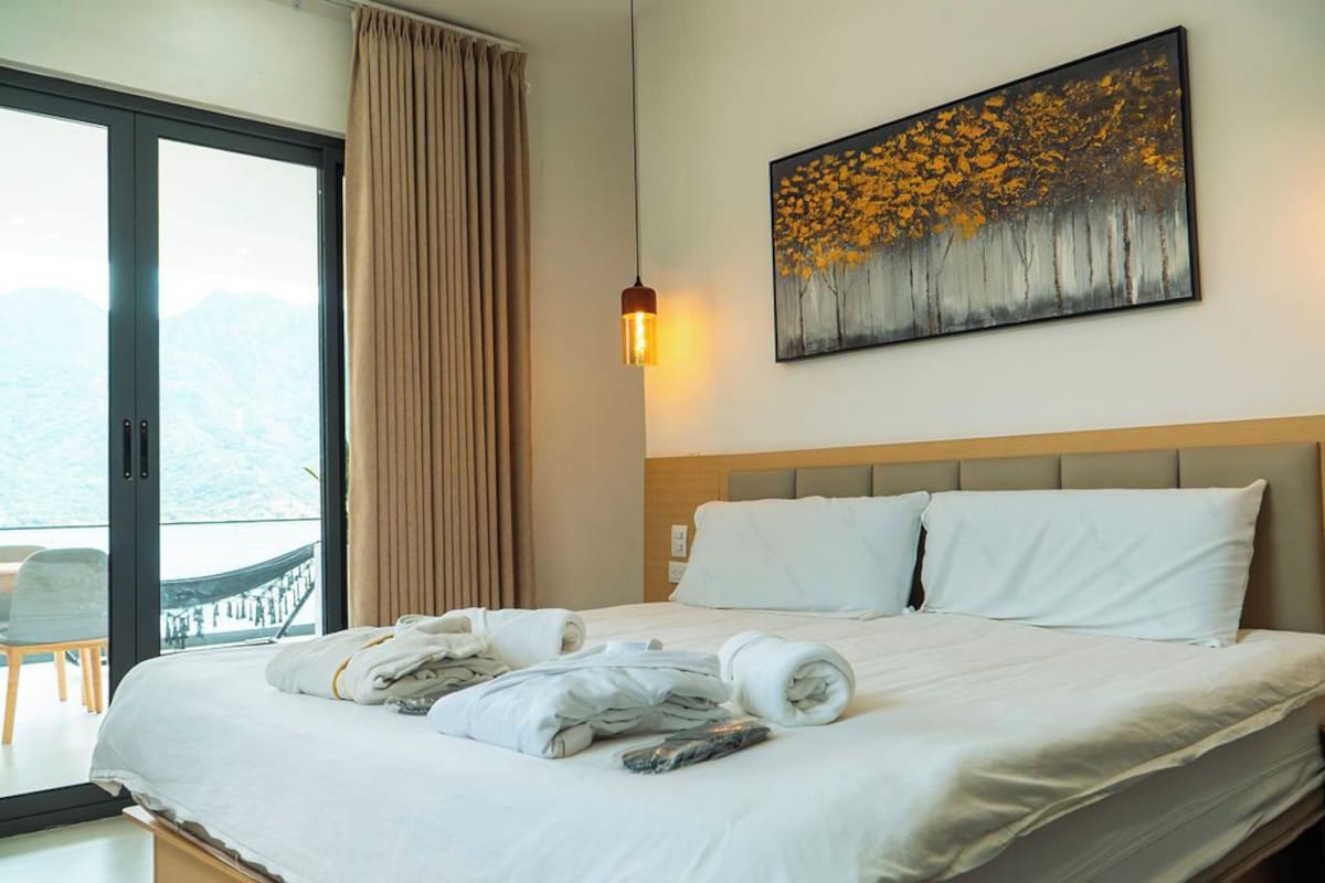 Een hotelkamer met een bed, een schilderij en uitzicht op bergen.