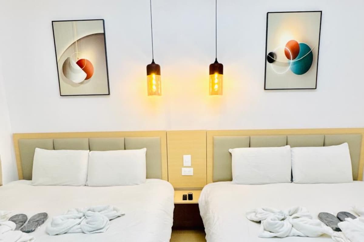 Een hotelkamer met twee bedden, een lichtgekleurd hoofdeinde en kunst aan de muur.