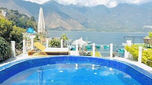 A swimming pool with a view of mountains and a body of water. - Luxury Atitlan Apartamentos  (San Pedro La Laguna)