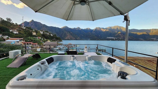 A hot tub with a mountain view, a deck with lounge chairs, and a pool area. - Luxury Atitlan Apartamentos  (San Pedro La Laguna)