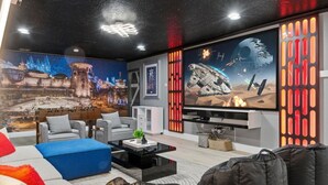 Ein modernes Wohnzimmer mit großem Flachbildfernseher, bequemen Sitzmöglichkeiten und Wandbildern zum Thema Star Wars.