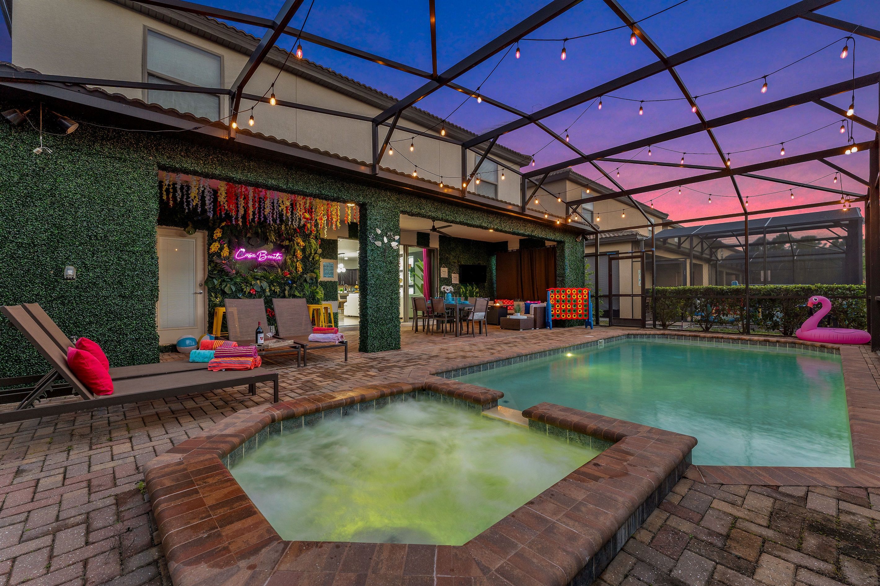 An indoor swimming pool with a hot tub, surrounded by lounge chairs and a covered patio area.
