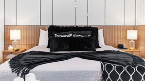 Ein Hotelzimmer mit einem Bett, zwei Nachttischen, einem Holz-Kopfteil und einem großen Fenster.