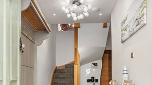 Ein schmales Entree mit Treppe, einer Bank, einem kleinen Tisch mit Handtuch und einer Wanduhr.