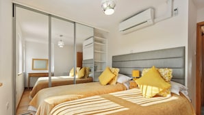 Ein Hotelzimmer mit zwei Betten, einem großen Spiegel, einem Kleiderschrank und einer Klimaanlage.