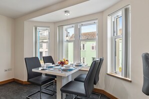 A dining area with a table, chairs, and a fruit bowl. - Sea and Steam - Close to Village and Beach (Saundersfoot)