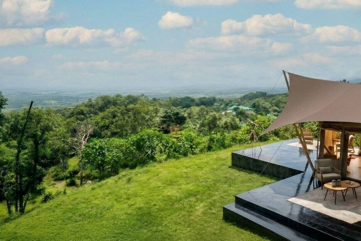 A modern outdoor lounge area with a view of a lush landscape.