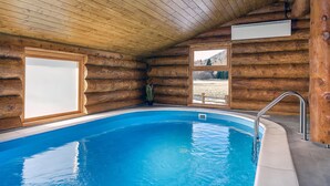 Una cabaña de madera con piscina, paredes de madera y una ventana.
