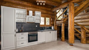 Una cocina moderna con muebles blancos, electrodomésticos de acero inoxidable y estructura de troncos de madera.