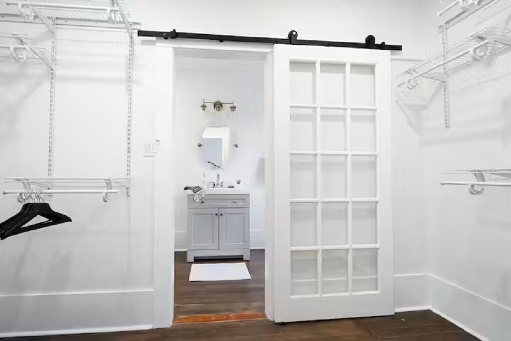 Una habitación blanca con una puerta corredera, un armario blanco y una percha.