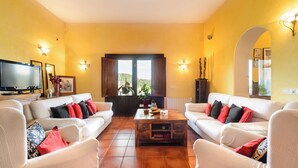 Un salón con dos sofás blancos, una mesa de centro y un televisor.