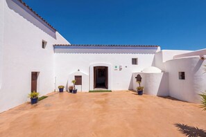 Un pati amb un edifici blanc, una porta i plantes en testos.