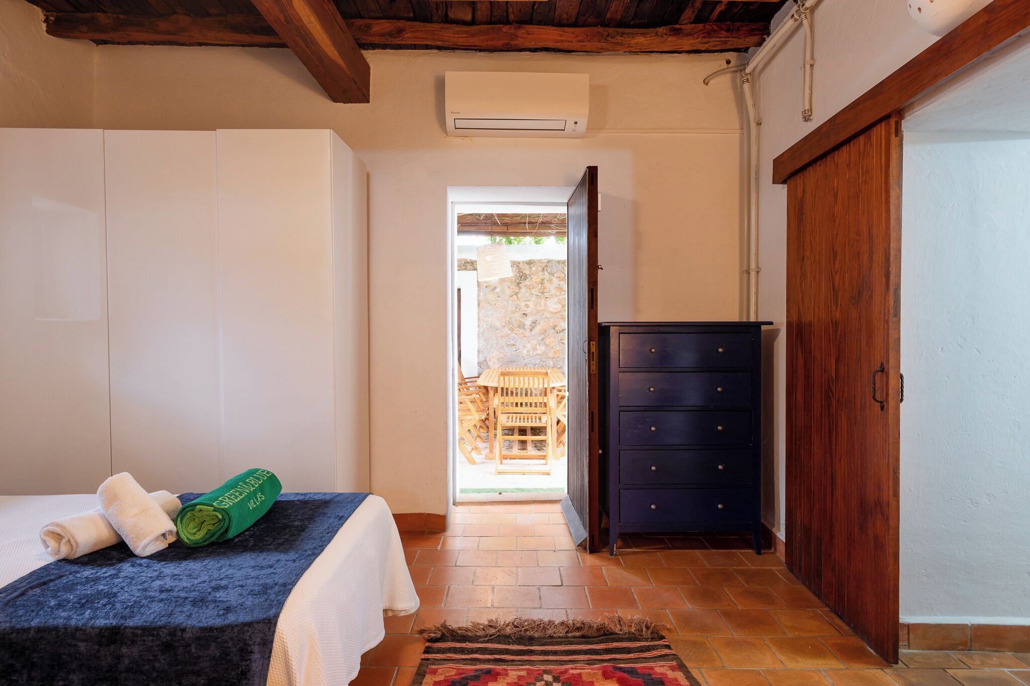 Un dormitorio con una cama, un aparador de madera, un armario y un equipo de aire acondicionado.